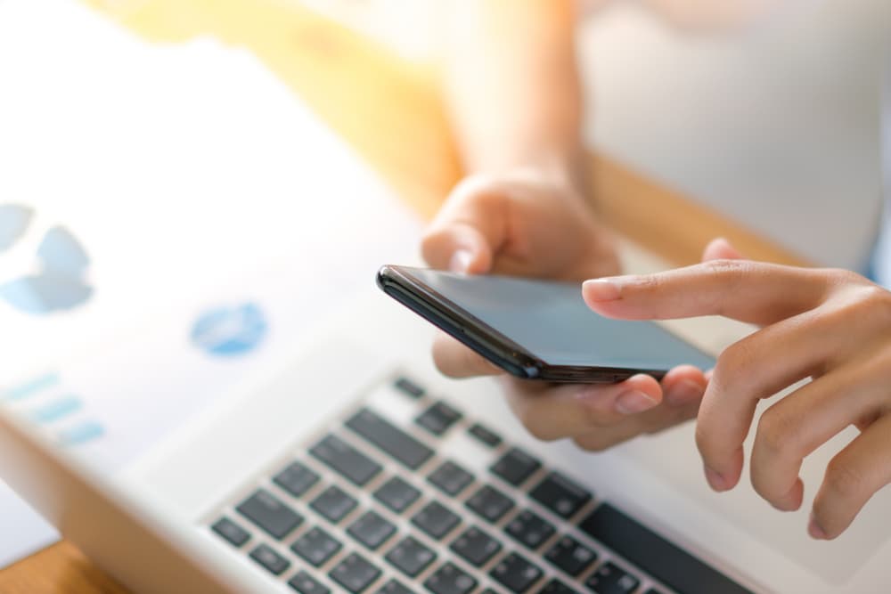 mano-mujer-negocios-graficos-financieros-telefono-movil-sobre-computadora-portatil-tabla-1-1