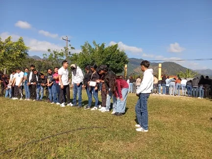 jóvenes en fila, tomados de la mano/agachados en actividad grupal al aire libre
