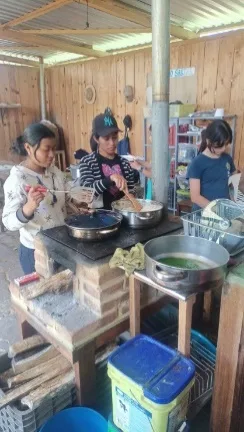 mujeres cocinando sobre fogón de leña, en ollas de metal
