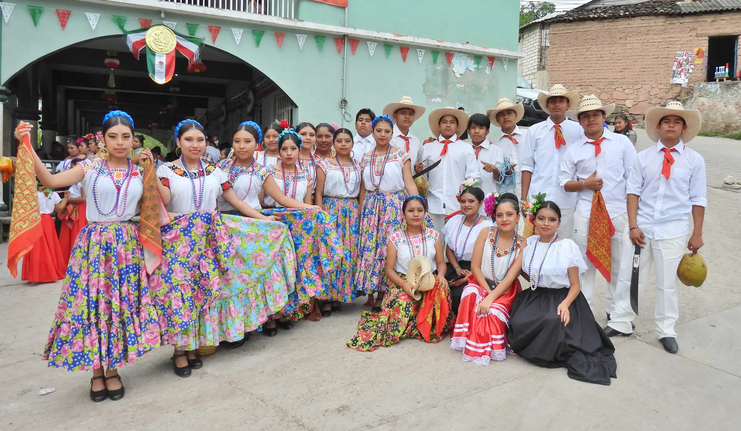 Grupo de bailarines con vestuario de colores y sombreros posando tras la presentación