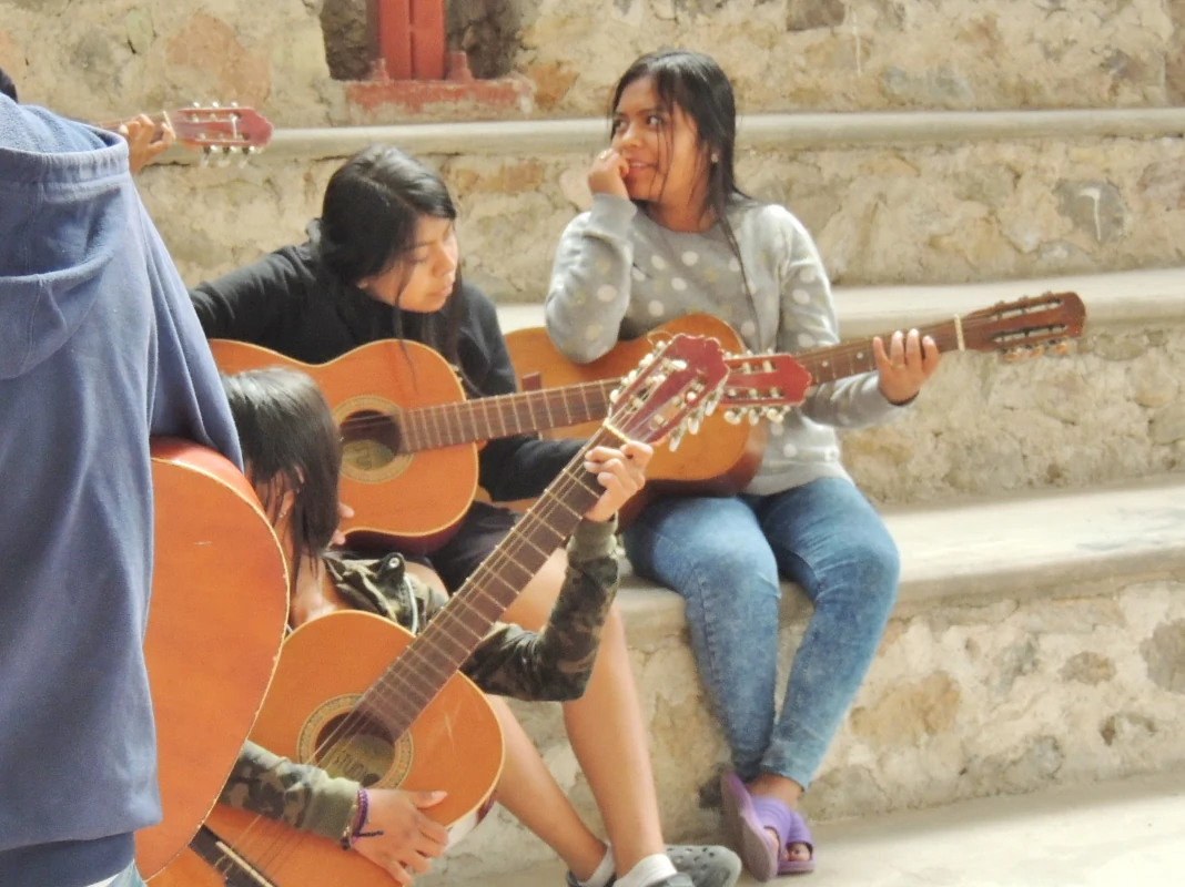Alumnas tocando guitarra sentadas en las gradas