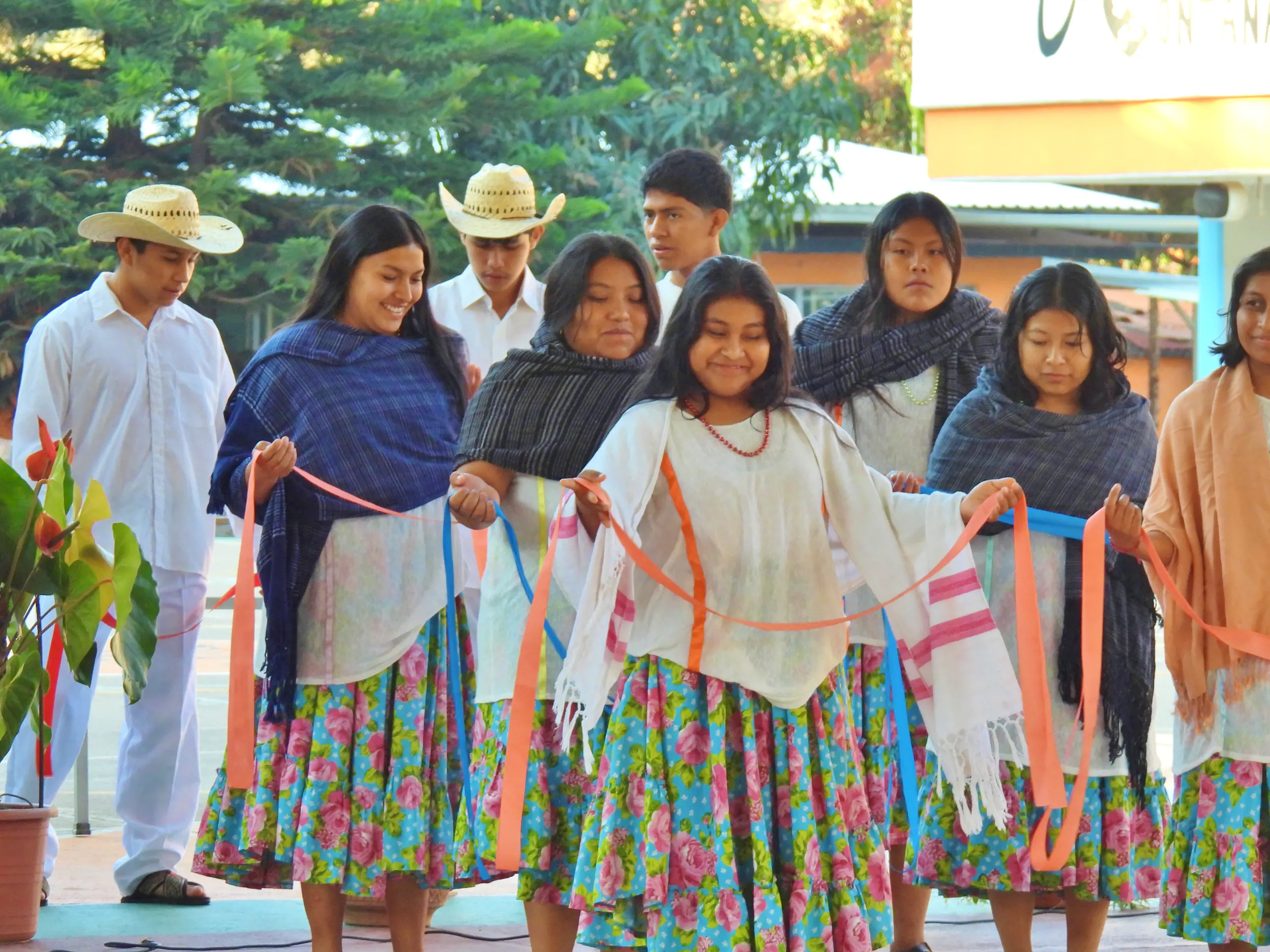 Alumnas con rebozos y faldas de colores y alumnos con sombrero en una presentación