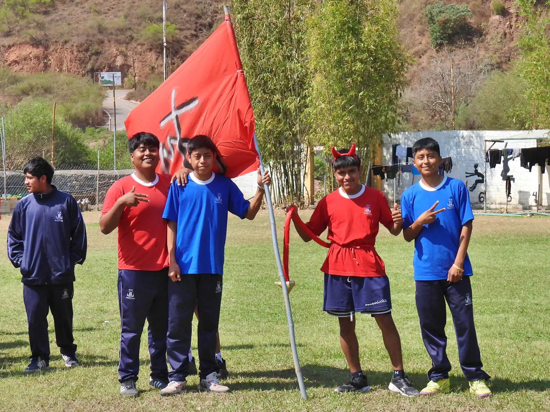 Alumnos con playera roja y azul de la fiesta atlética, con una bandera roja
