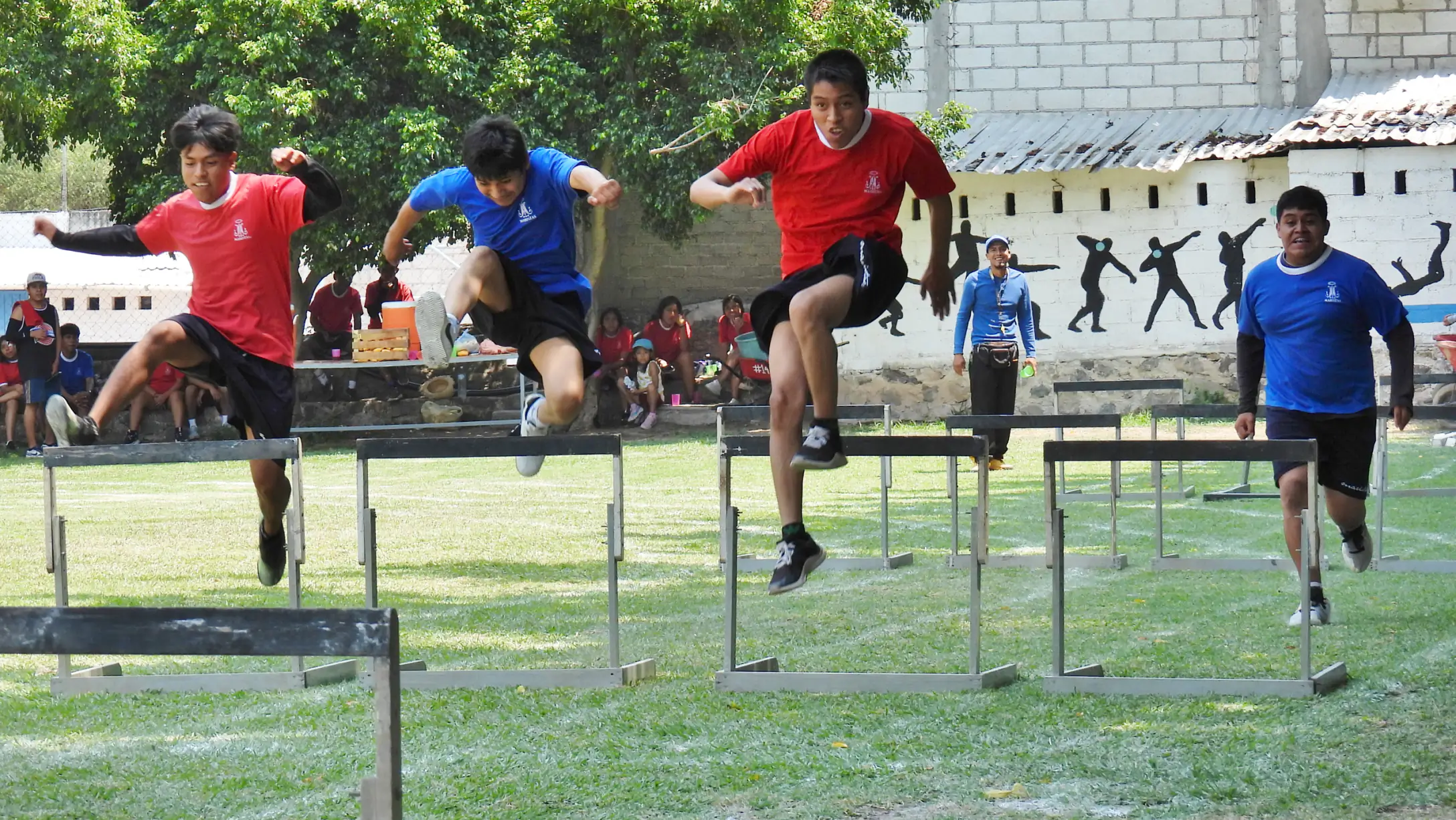 Alumnos saltando vallas en la pista