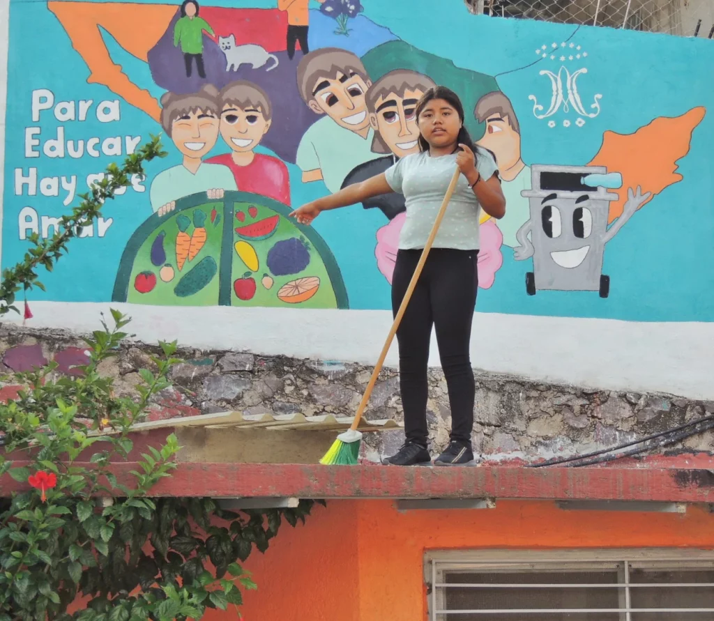Alumna barriendo frente a un mural