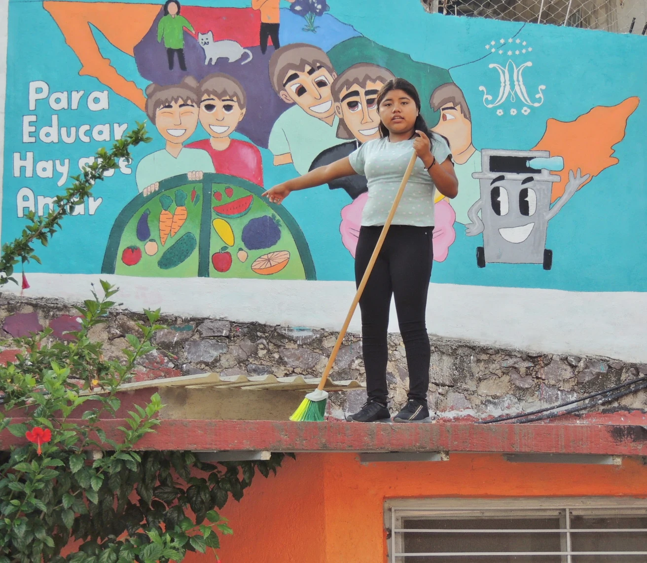 Alumna barriendo frente a un mural