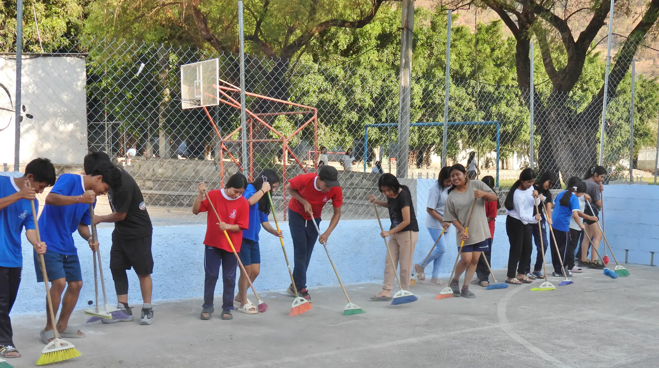 Alumnos barriendo la cancha en fila