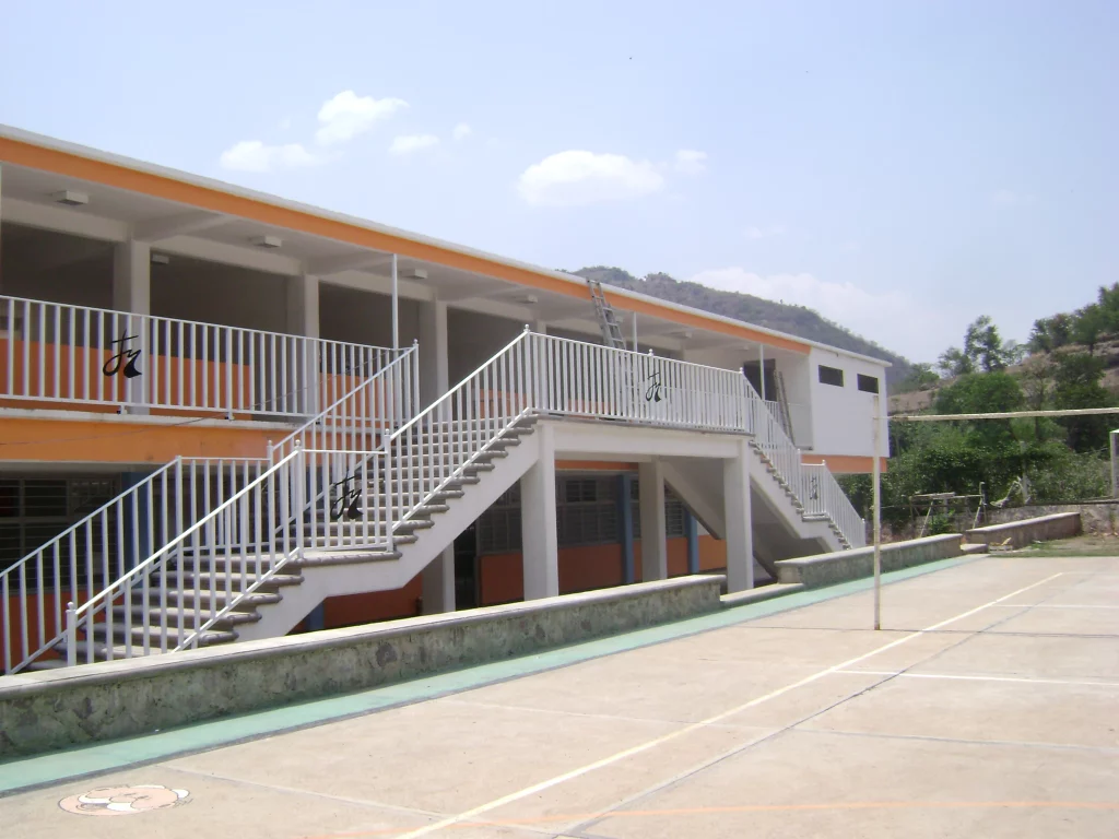 Cancha de voleibol junto al edificio de aulas, con sus escaleras y barandales blancos