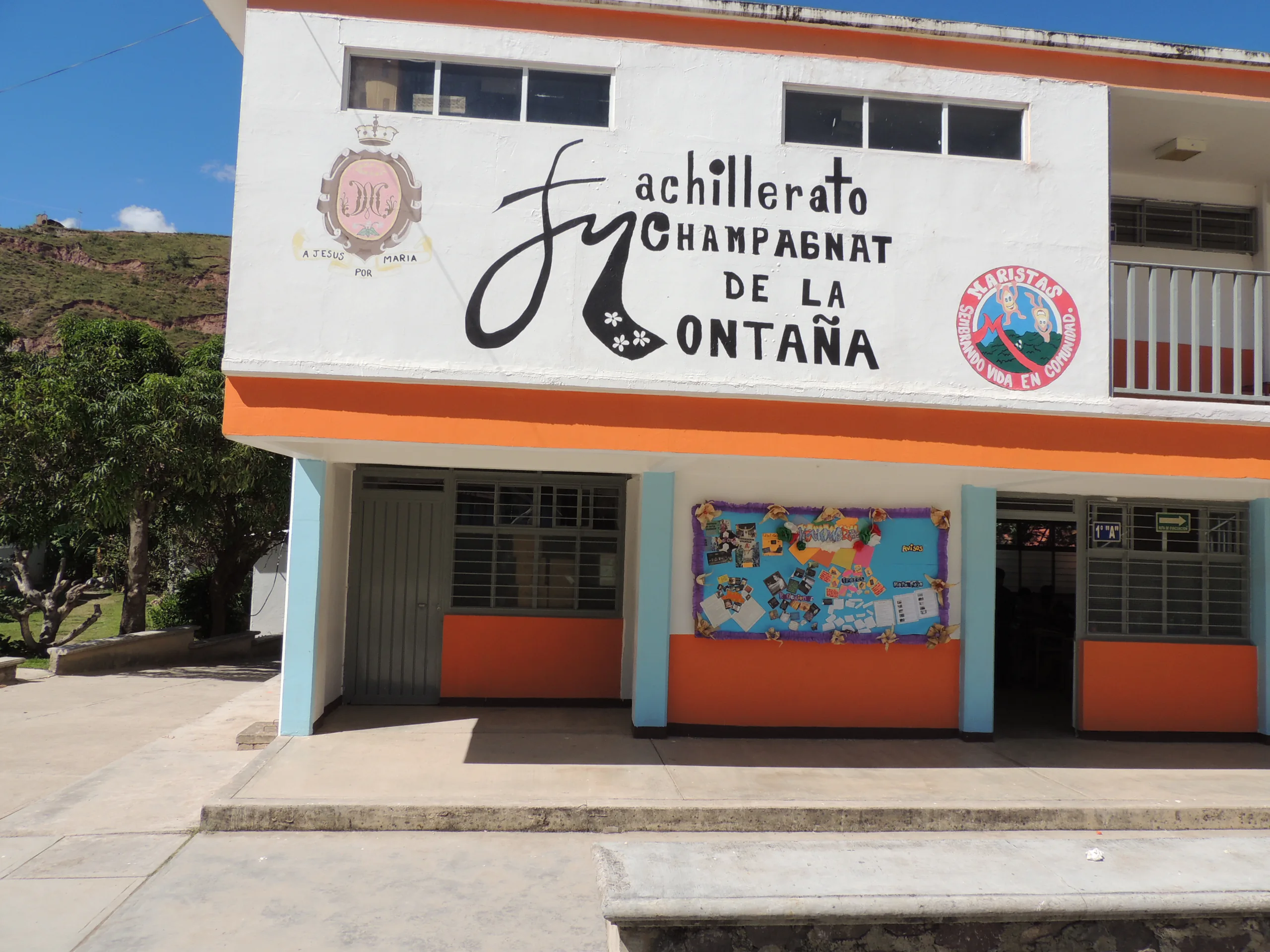 Fachada del edificio con el letrero pintado «Bachillerato Champagnat de la Montaña» y el emblema marista
