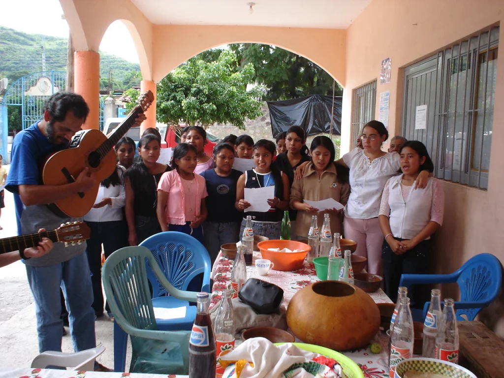 Grupo de personas con guitarras y pan de dulce en un corredor, durante un encuentro