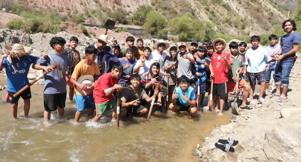Decenas de jóvenes en el cauce de un río trabajando juntos