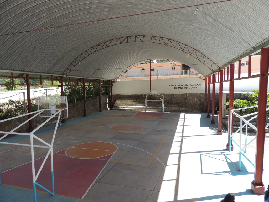 Cancha techada vista desde dentro, con tableros y el muro del fondo
