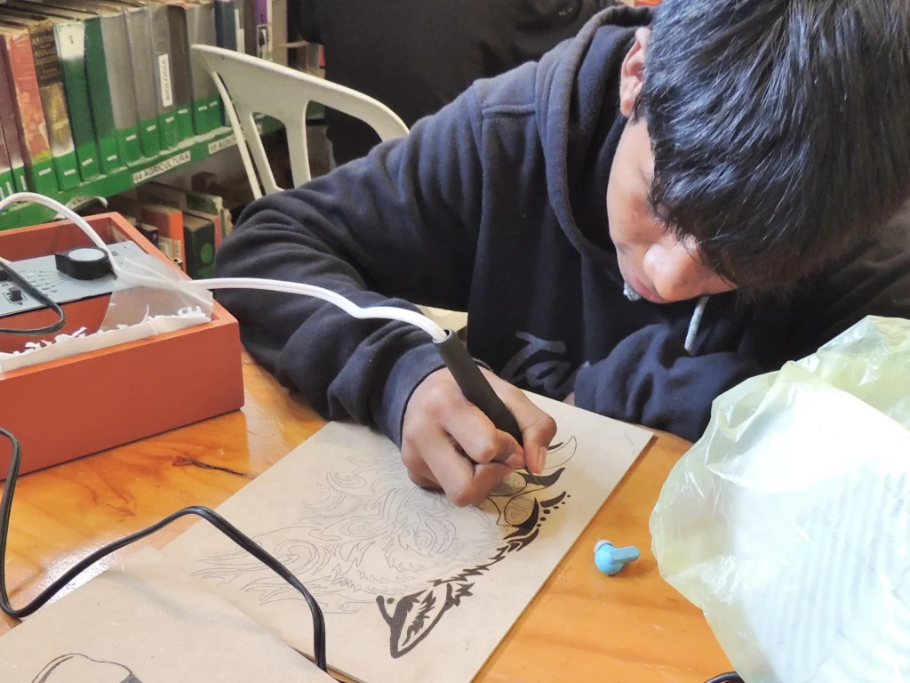 Alumno pirograbando un dibujo sobre madera en la biblioteca